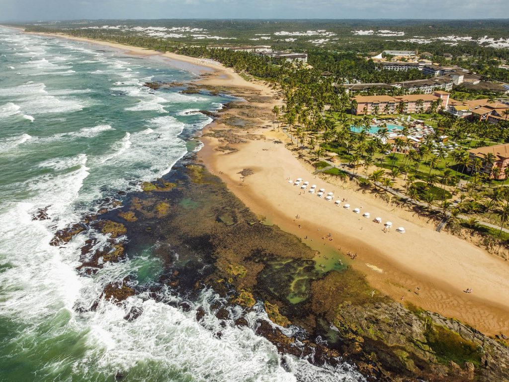 mar em meio as pedras, com resort ao fundo.