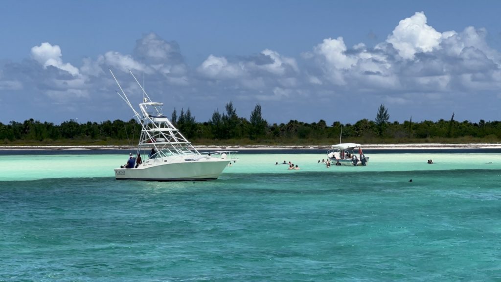 Praia de Cozumel com tons tons de água e ym barco