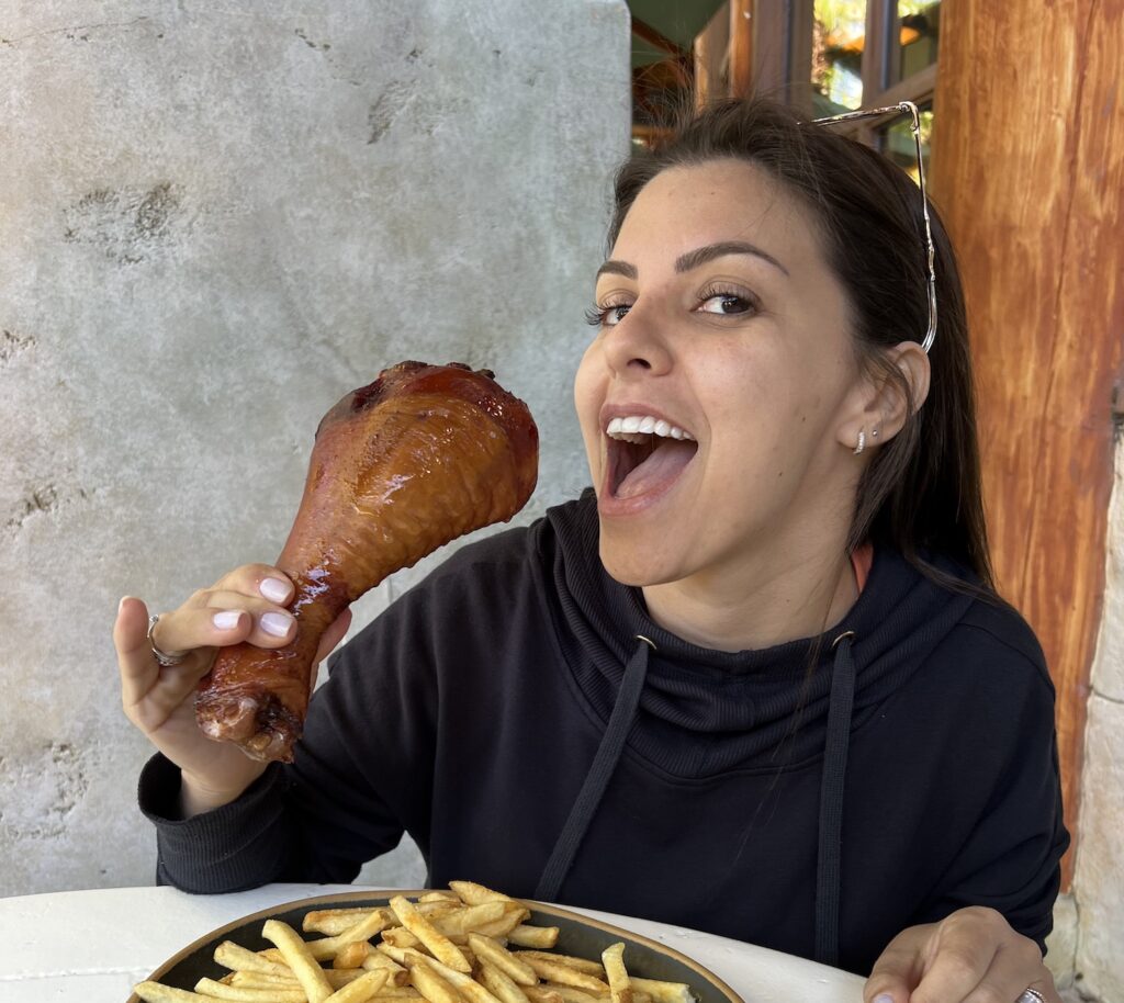 mulher comendo uma coxa de peru com batata frita