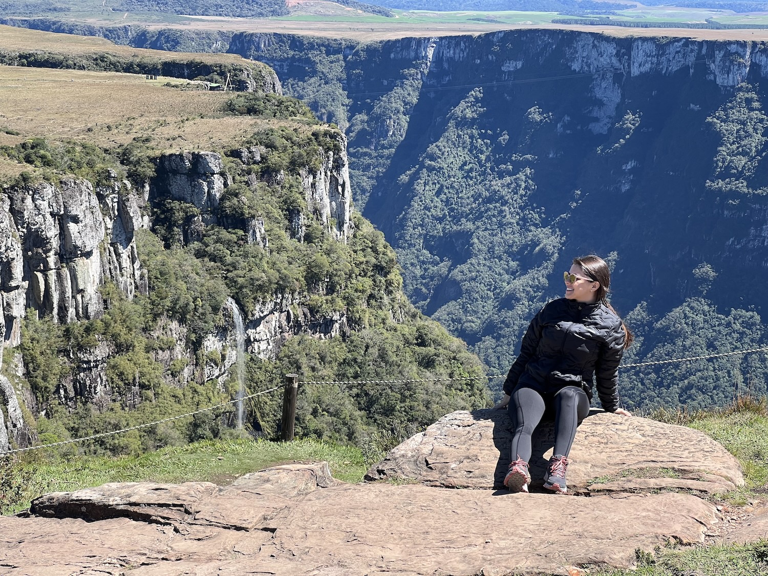 Mulher vestida de preto, sentada em meio aos cânions