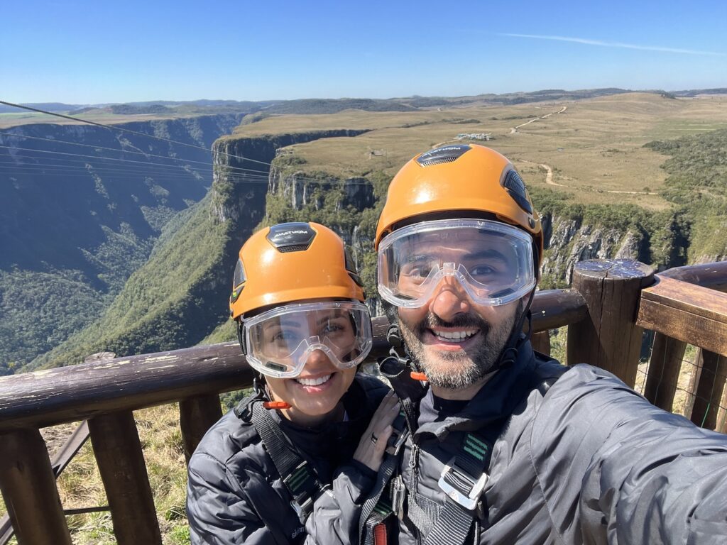 Selfie de um casal em meio a natureza, com equipamentos de segurança