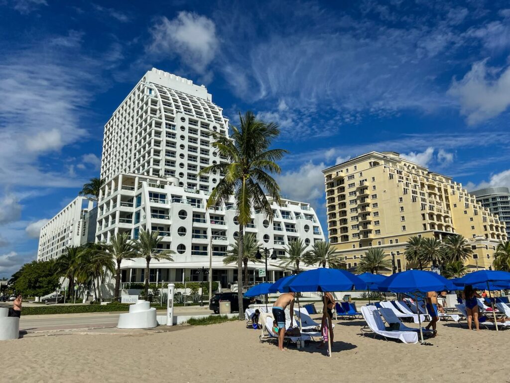 cadeiras e guarda-sol na areia com hotel ao fundo