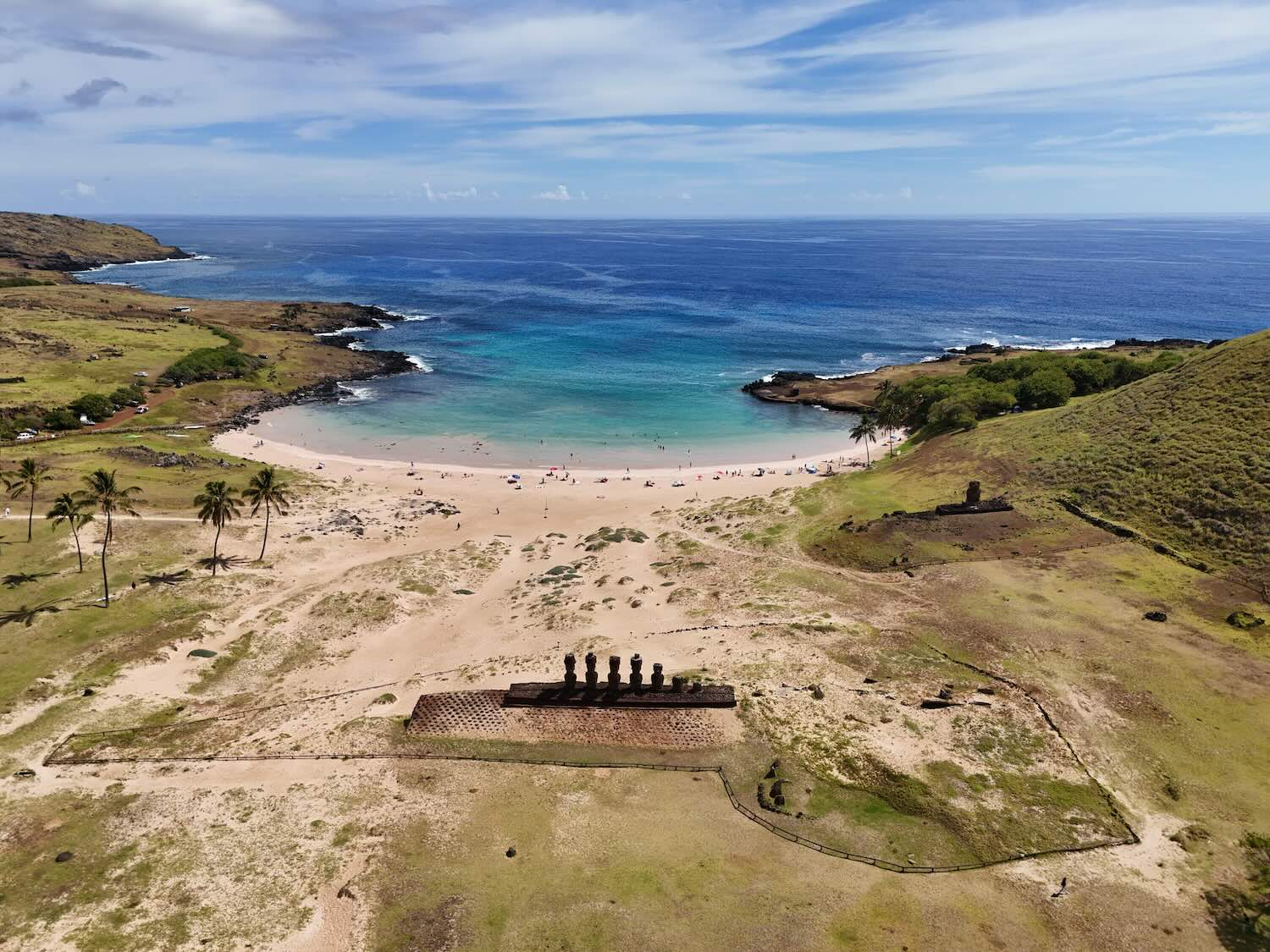 imagem aérea de uma praia com estátuas de moais