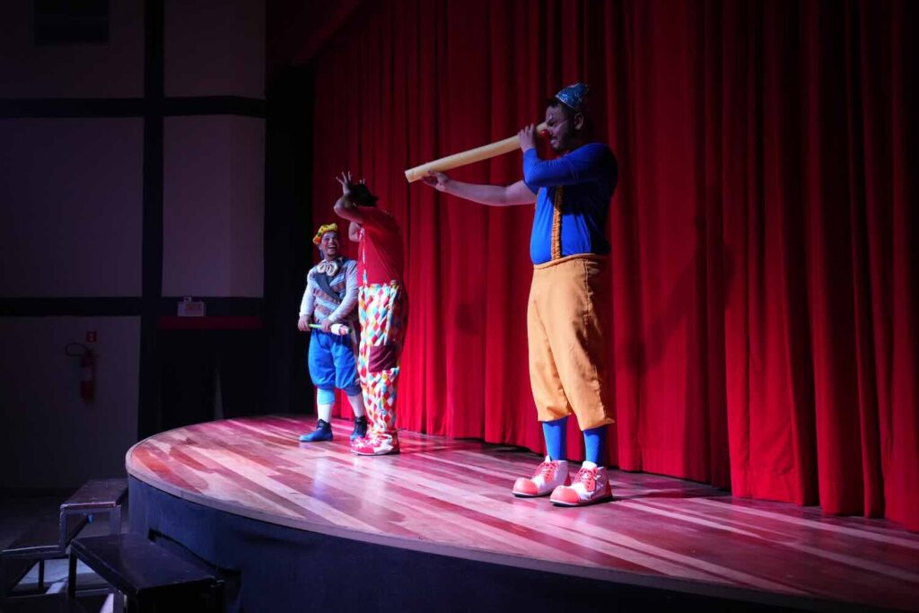 atores em um palco com fundo vermelho