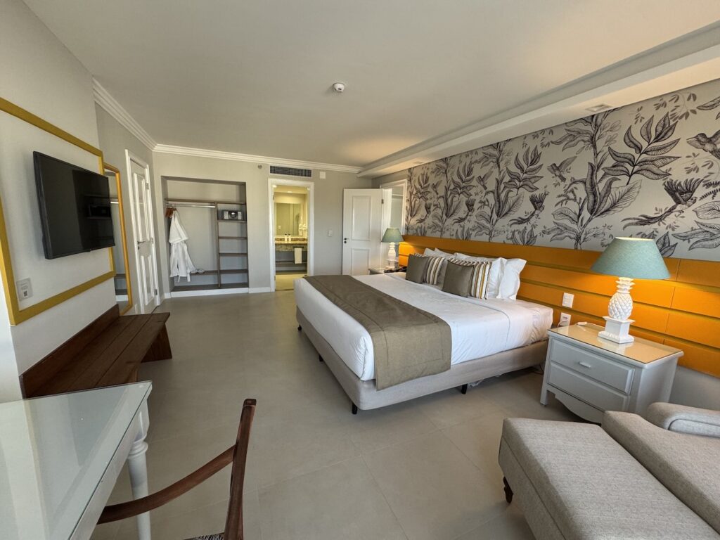 quarto de hotel espaçoso, com cama de casal, televisão e sofá