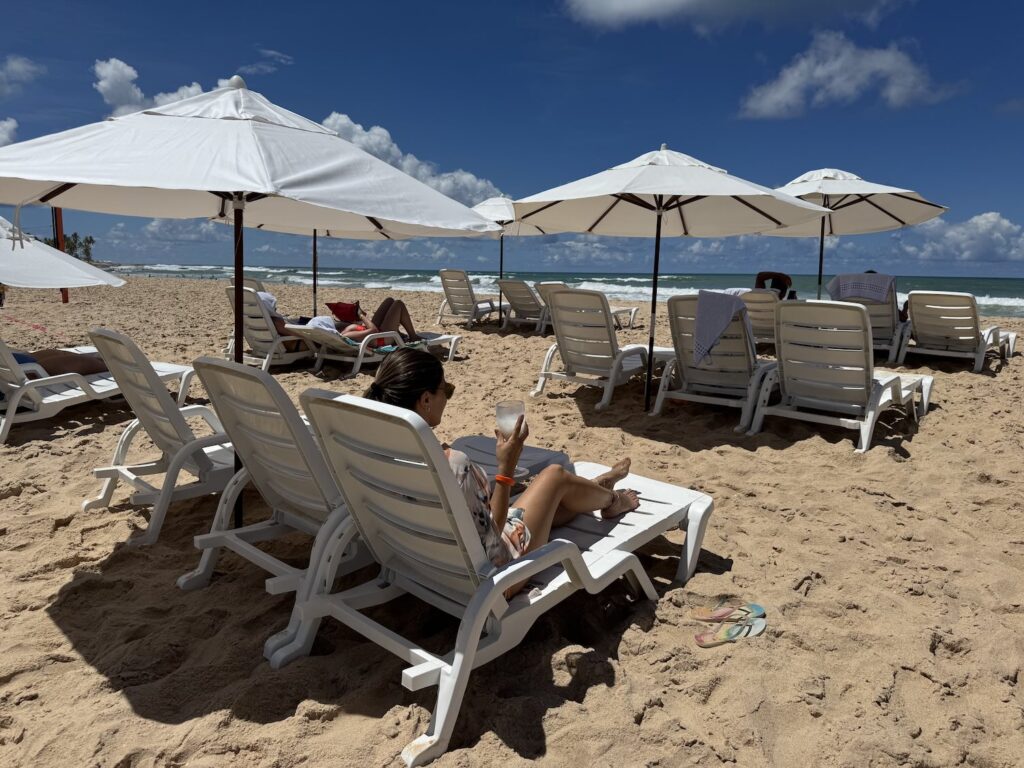 mulher sentada em cadeira de praia em frente ao mar