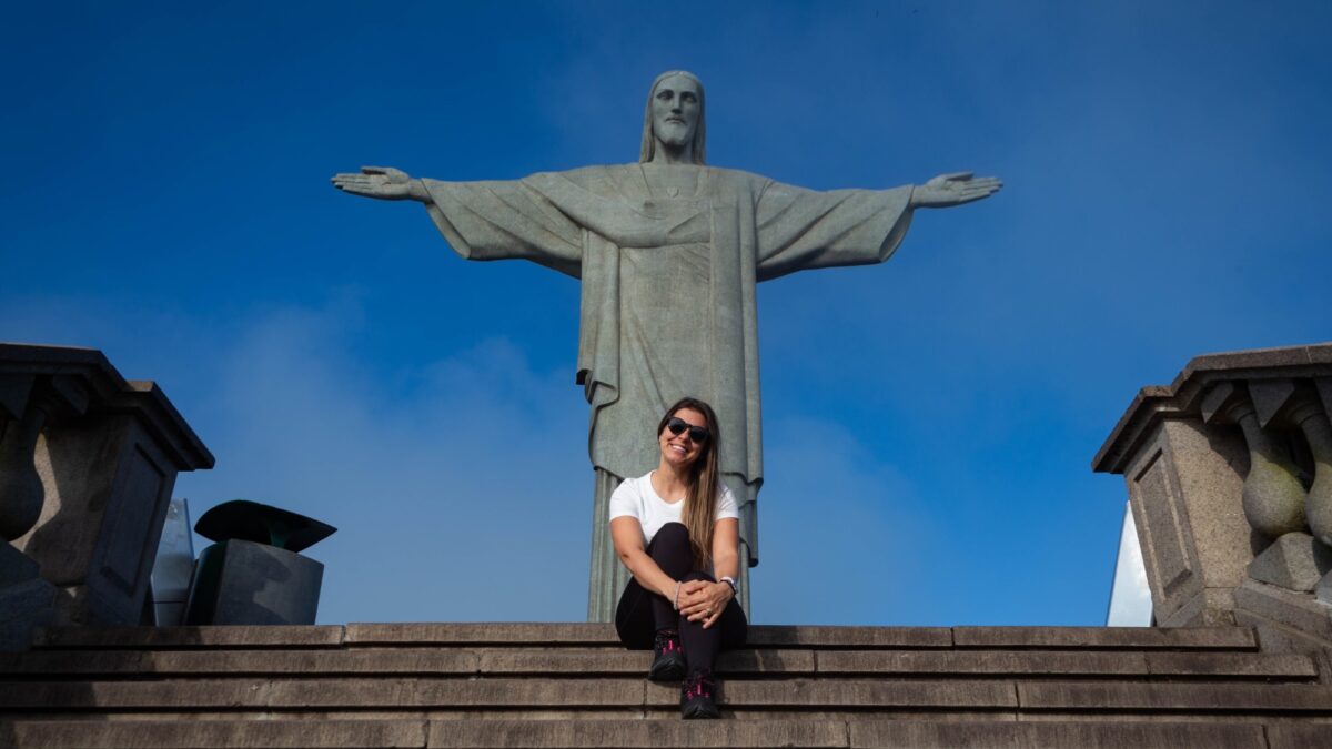 mulher sentada em frente a estatua do cristo redentor no rio de janeiro