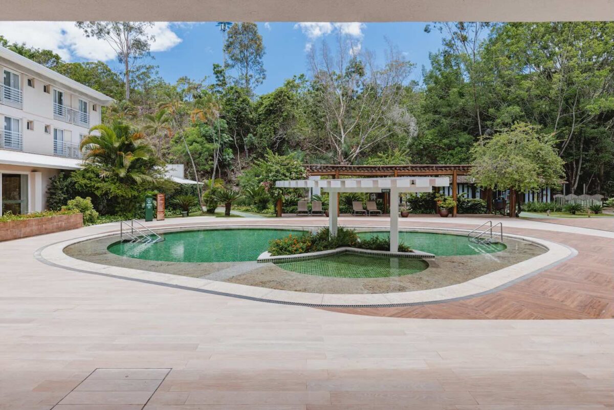 piscina de um hotel com vegetação ao fundo