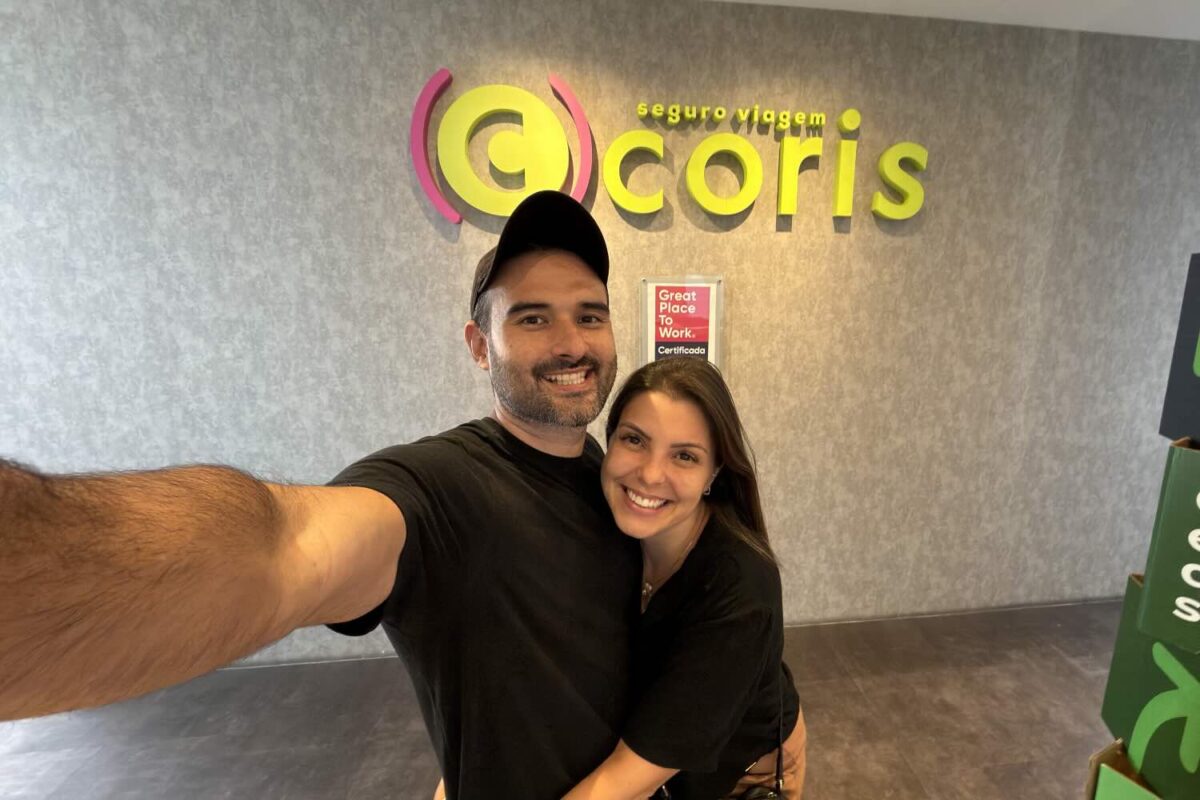 casal abraçado em frente a um letreiro da martca coris